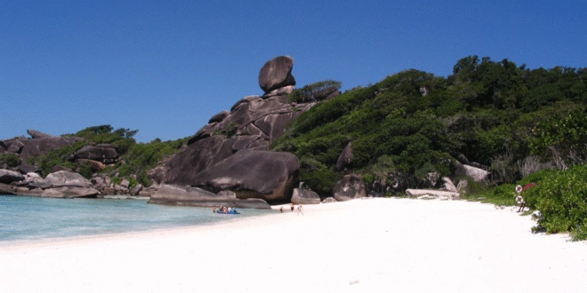 Skalistá pláž s bílým pískem a velkými kameny na Seychellských ostrovech.