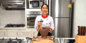 Mladá kuchařka s keramickým kladivem a tradičními nástroji na přípravu thajských a kambodžských jídel.